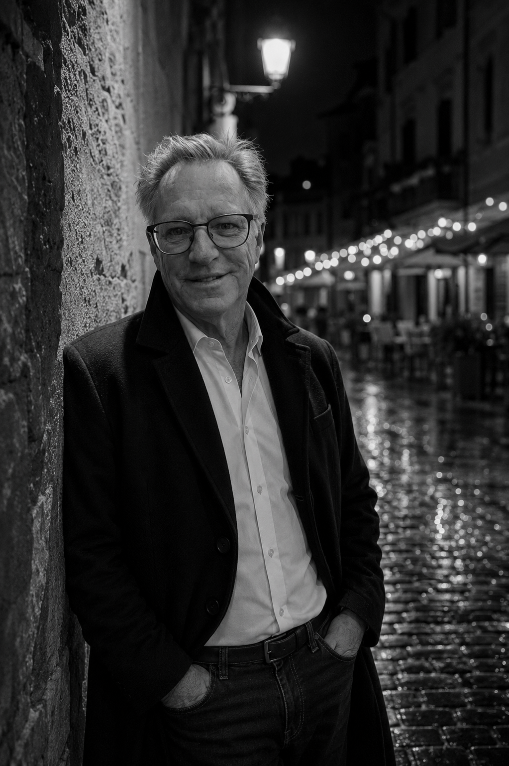 Black-and-white portrait of Geno Andrews on a rain-slicked European street at night